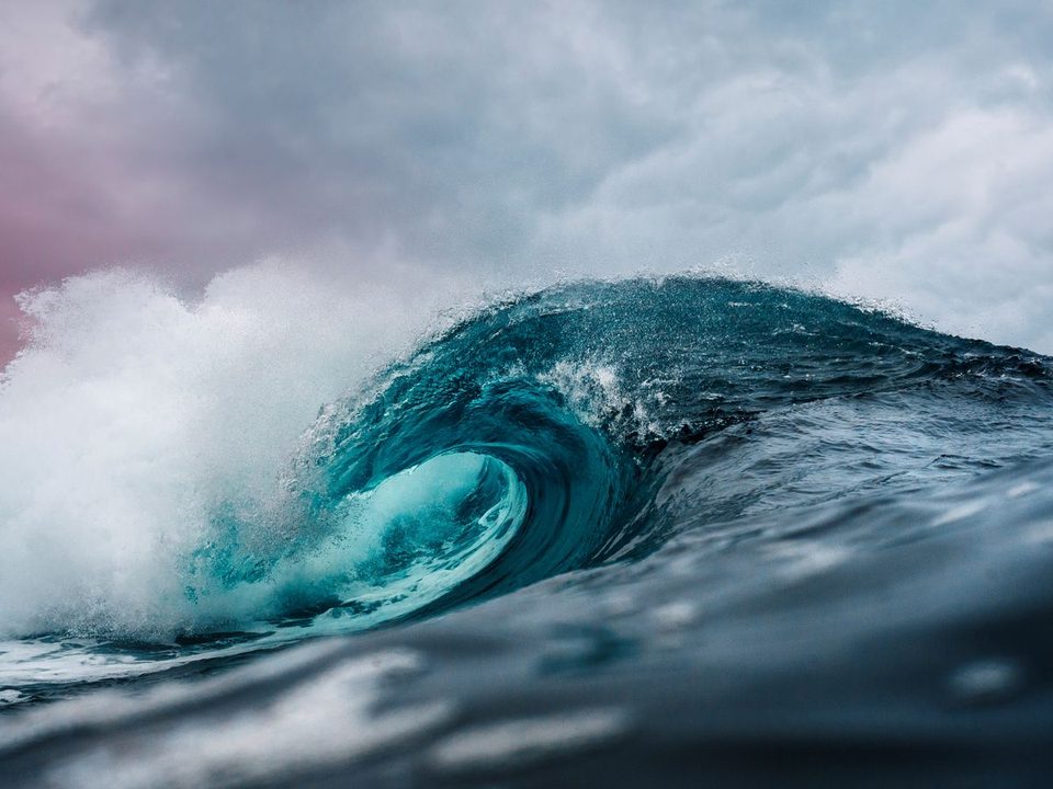 Heavy ocean waves under weather-bearing sky.